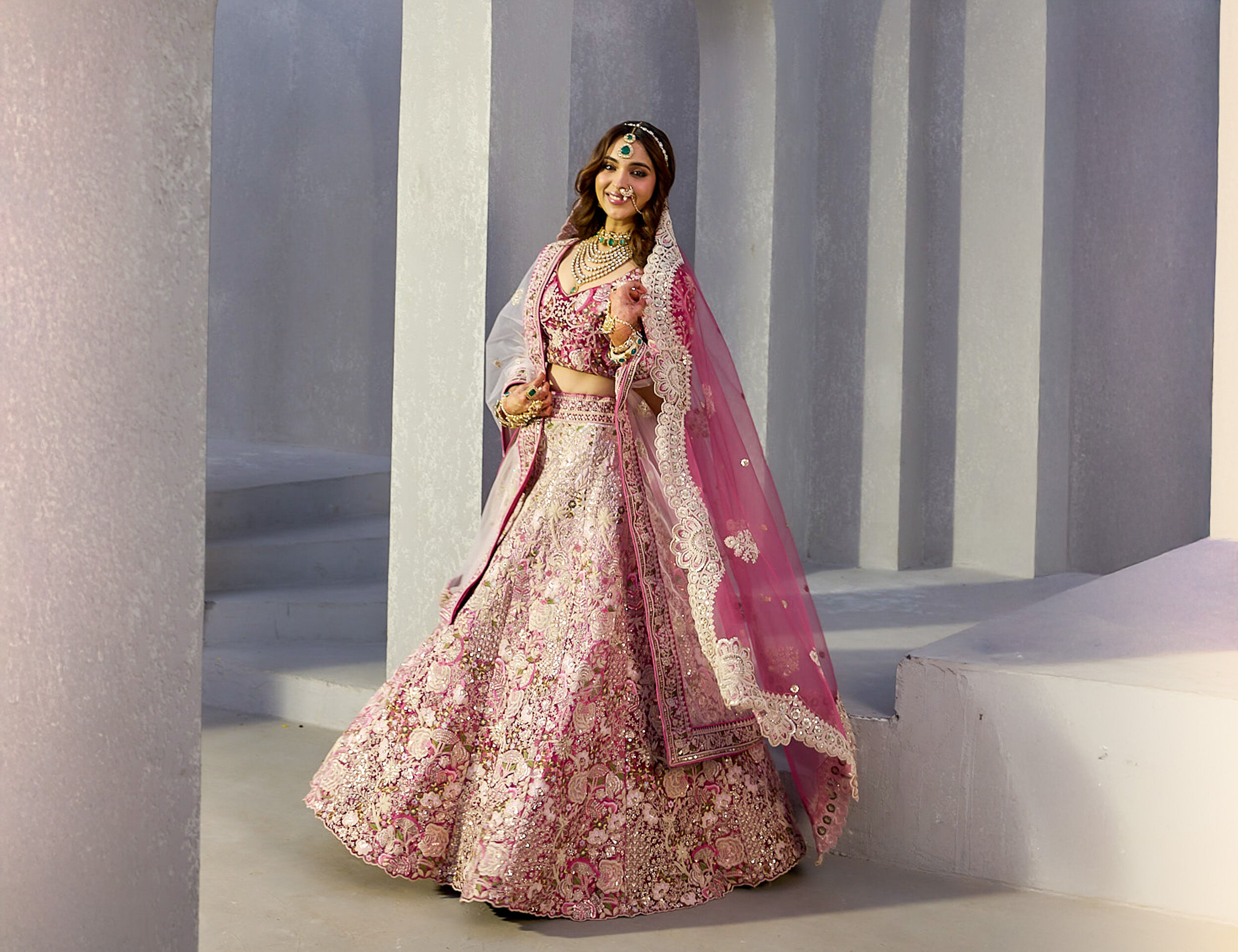 Woman in a stunning pink lehenga paired with a matching pink dupatta, ideal for a graceful bridal outfit.